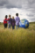 Four children stand together in a field, looking at a large globe. Symbolizes global responsibility and the future of the earth.